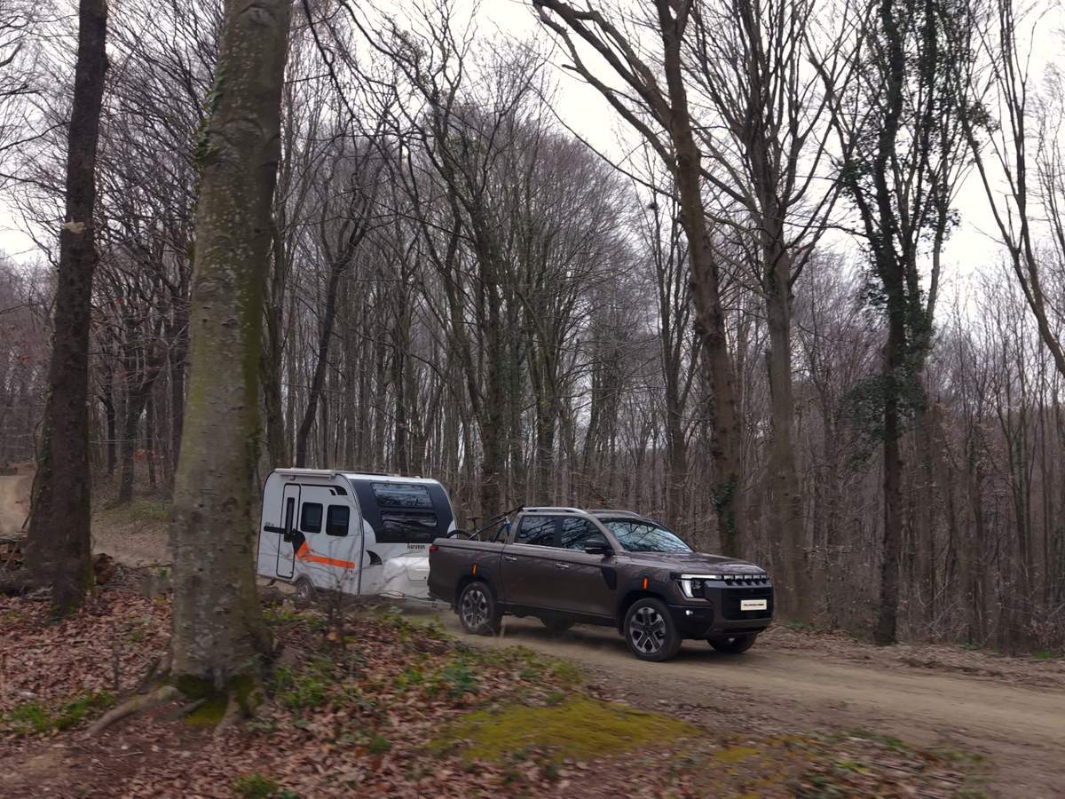 KGM Musso med vleko počitniške prikolice na gozdni poti