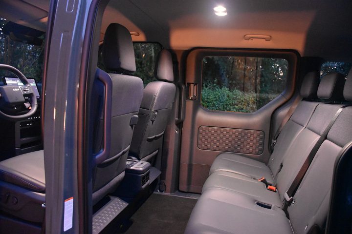 Temno zelena električna Kia PV5 Passenger, parkirana v naravnem okolju - poudarek na prostorni kabini