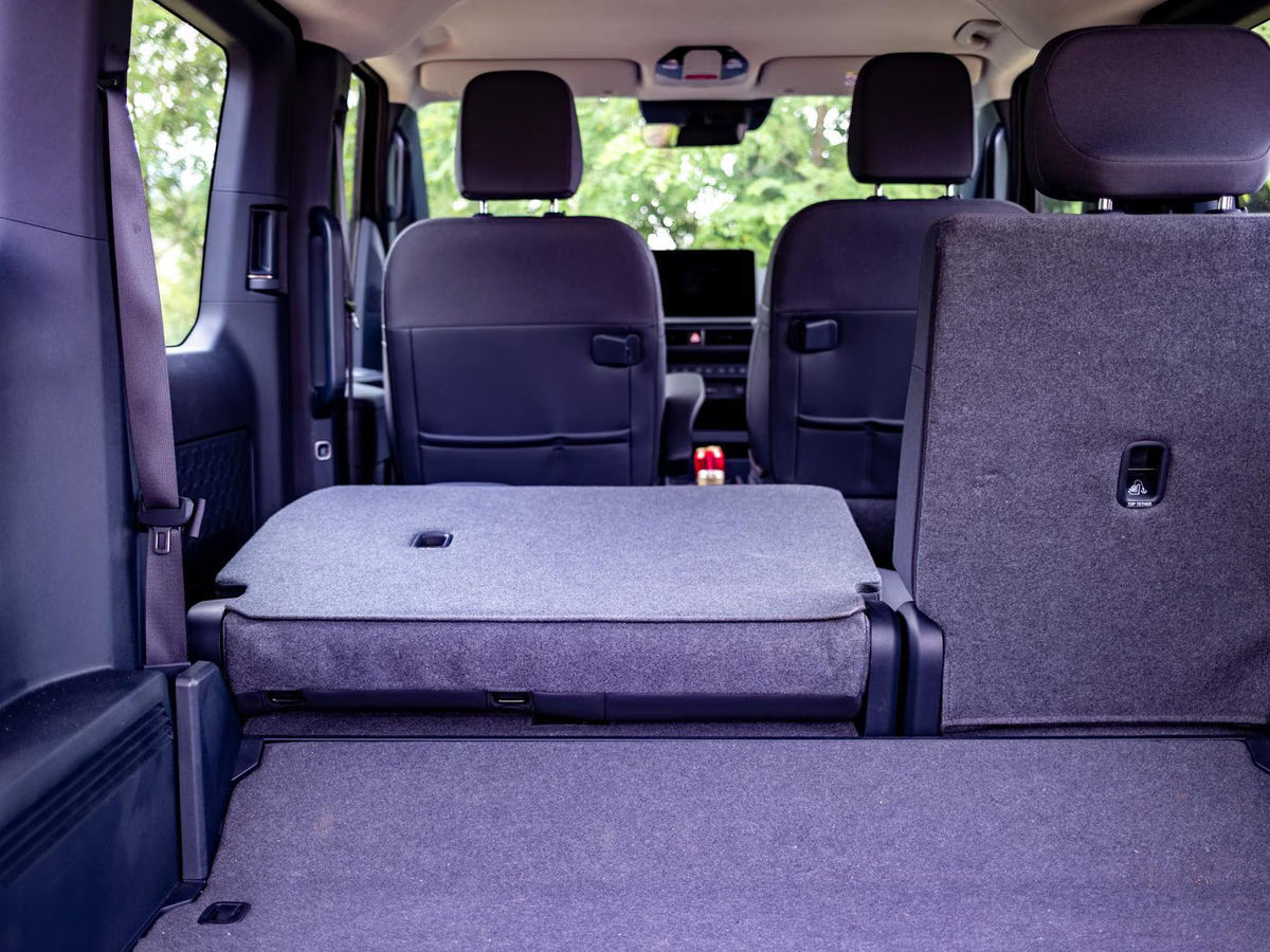 Prtljažni prostor modela Kia PV5 Passenger z delno podrtimi zadnjimi sedeži in povečano nakladalno površino.
